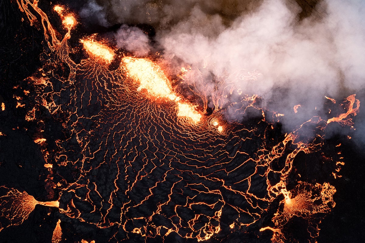 Close-up aerial view showing smoke and patterned yellow-white and black lava.