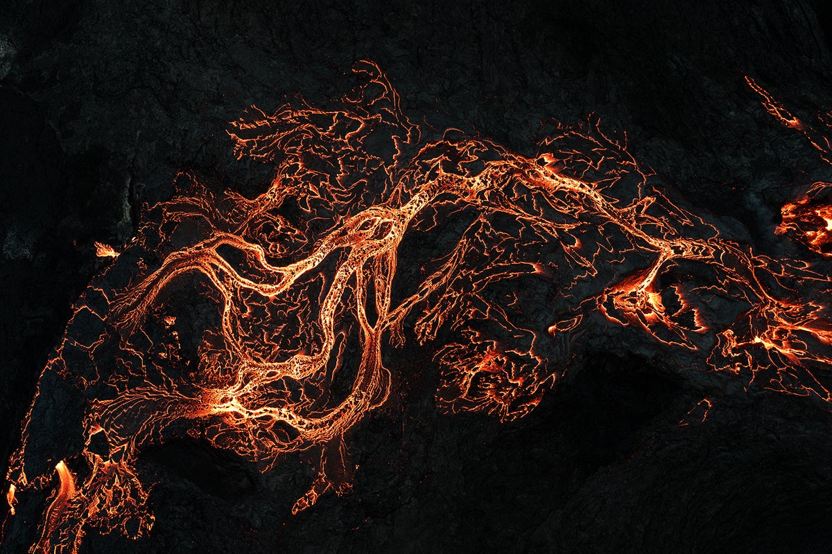 Close-up aerial view of yellow-red lava forming the shape of a branching river or stream.