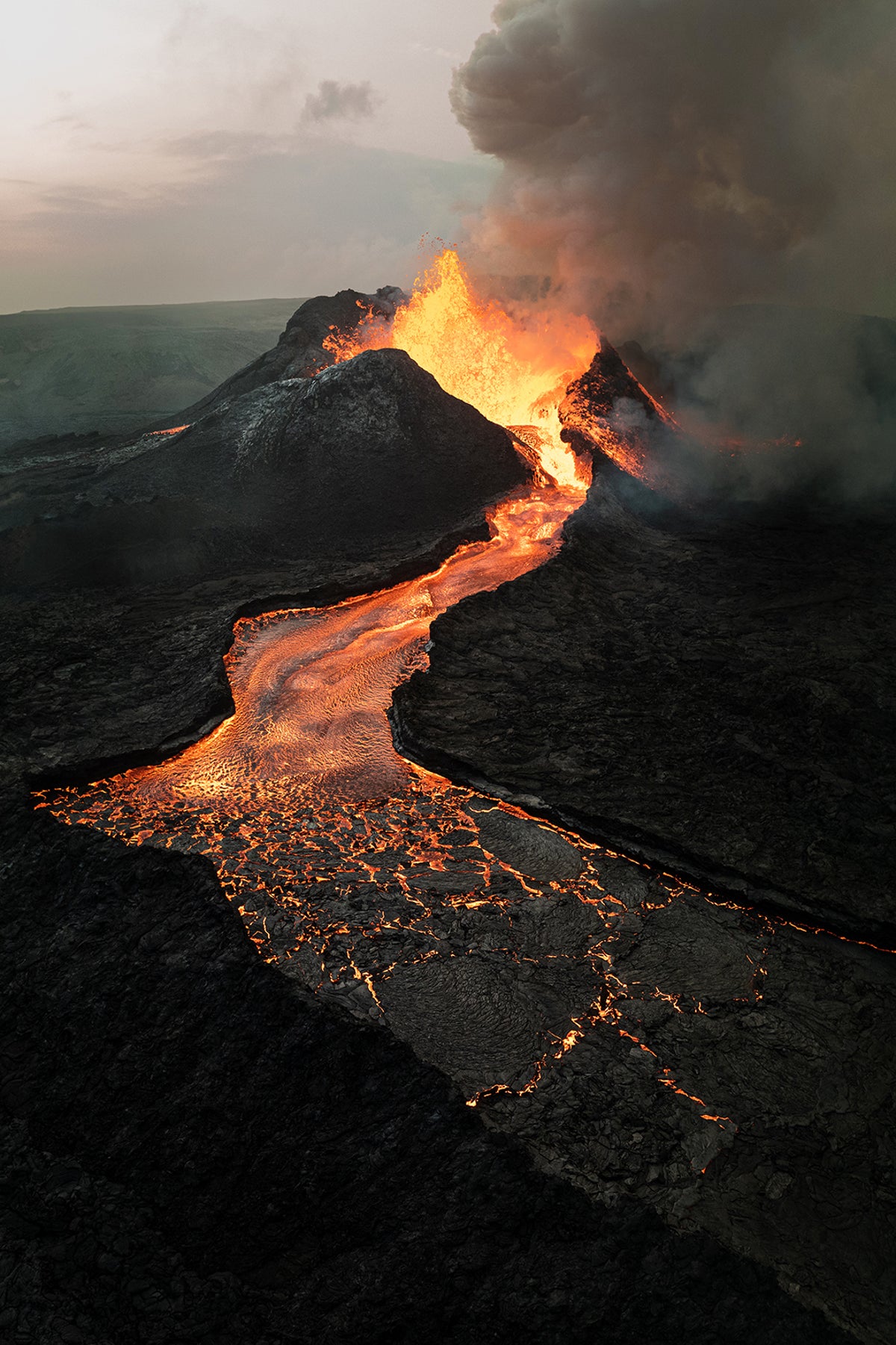 A volcano erupting with lava flowing out in a heavy single stream.