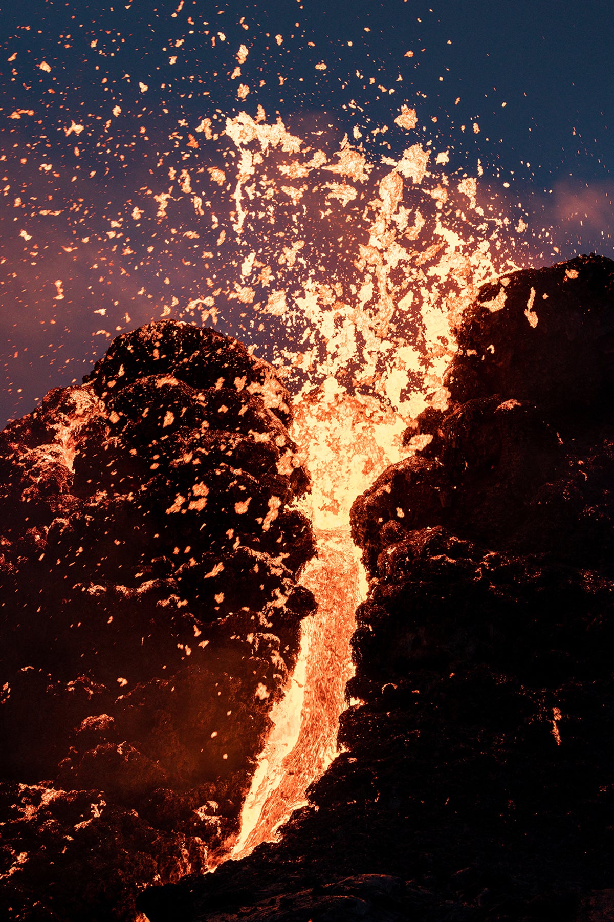 Close-up of yellow-red lava exploding out of the crater of a volcano.