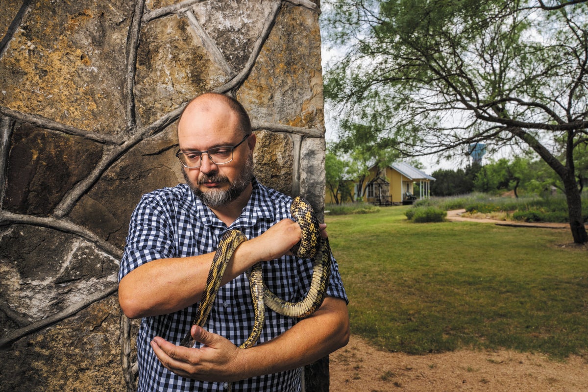 Man holding a snake in an outdoor setting.