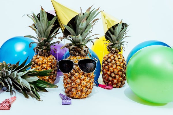 Three pineapples, one wearing sunglasses, and six colorful balloons