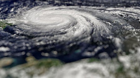 A view of Hurricane Maria on 9/20/2017. The image looks as if we're flying just above the hurricane and looking at it edge-on. Thick bands of white cloud spiral over the ocean.