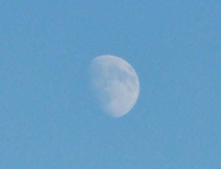 Image shows a ghostly moon in a blue sky