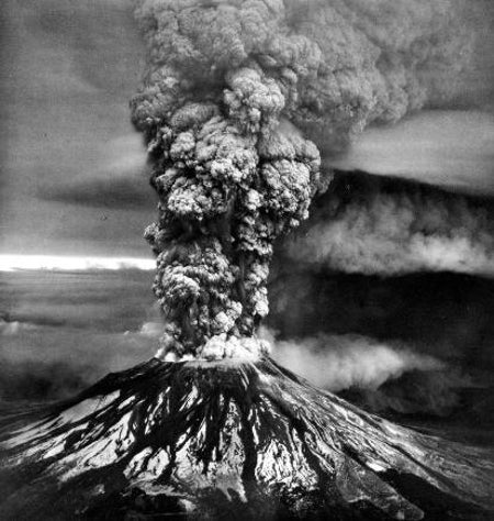 Black and white aerial image shows Mount St. Helens with a towering eruption cloud.