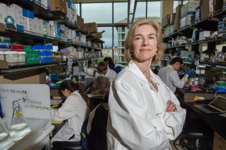 Jennifer Doudna with arms crossed in a white lab coat in a laboratory.