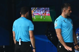 A referee checks the video assistant referee screen during a soccer match.