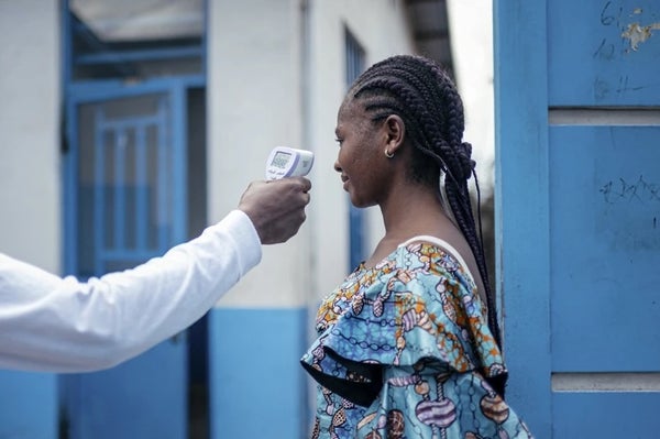A medical worker in the DRC checking the temperature of a woman using a a contactless infrared thermometer.