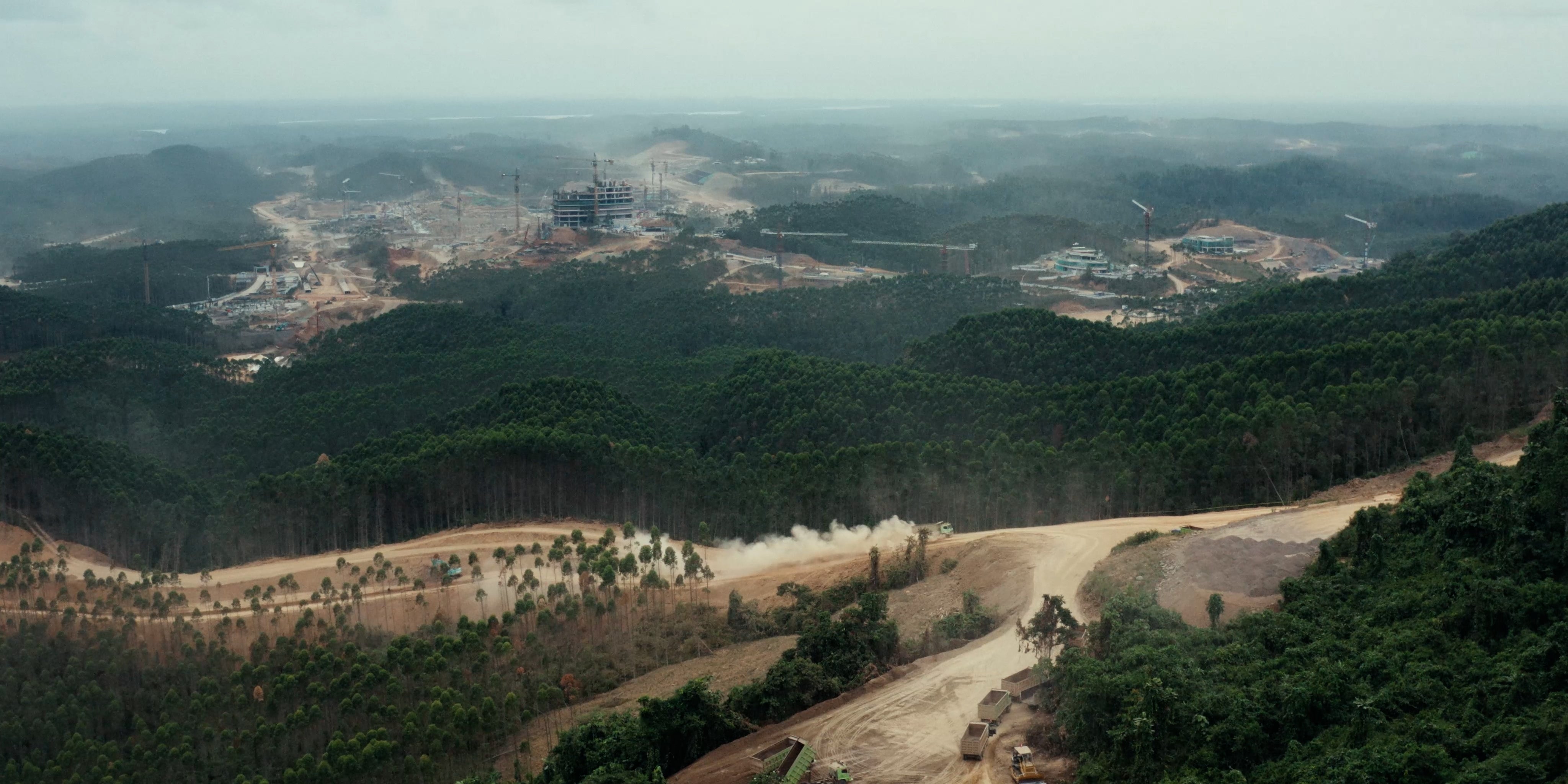 An aerial view of a rainforest that is being cleared by heavy construction equipment