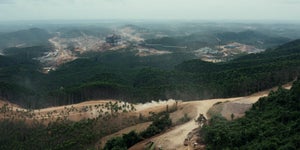 An aerial view of a rainforest that is being cleared by heavy construction equipment
