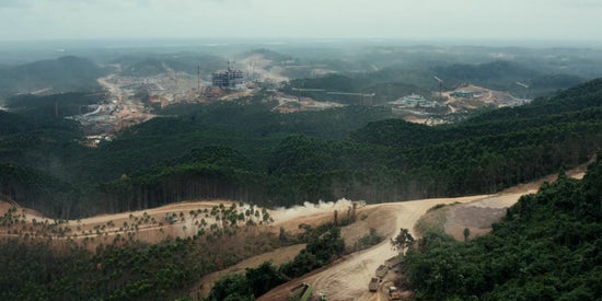 An aerial view of a rainforest that is being cleared by heavy construction equipment