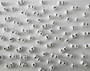Dice arrayed on a white surface displaying many prime numbers.