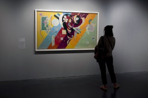 A woman stands next to the abstract painting entitled "Composition IX" (1936) by Russian artist Vassily Kandinsky at the Pompidou Center in Malaga.