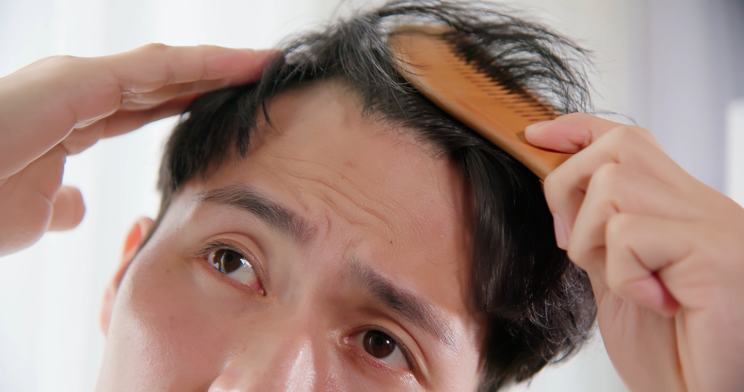 A man brushing unruly hair