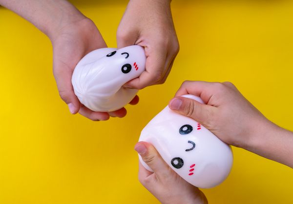 Kids playing with smiling squishies on a bright yellow background