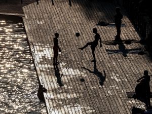 People kick a ball around near a lake in Kraków, Poland.