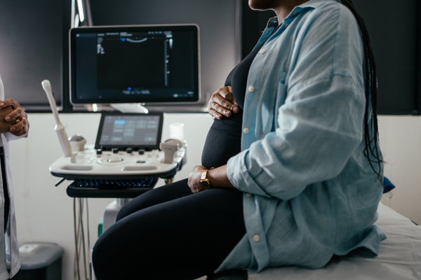 امرأة حامل تمسك بطنها أثناء فحص ما قبل الولادة.