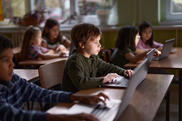 Kids in a classroom working on laptops.