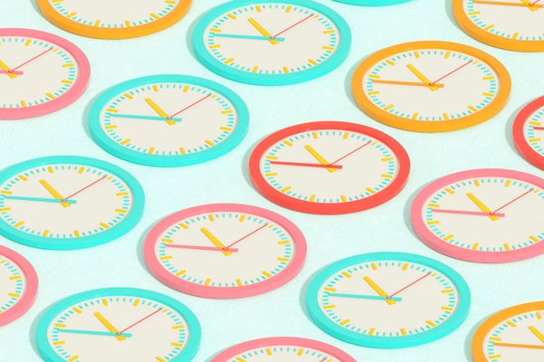 An array of colorful wall clocks viewed at a diagonal angle
