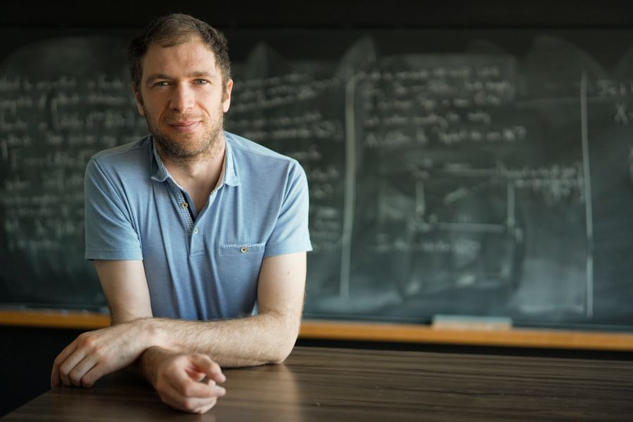 A sitting man faces nan perceiver pinch a blurry, equation-filled blackboard successful nan background