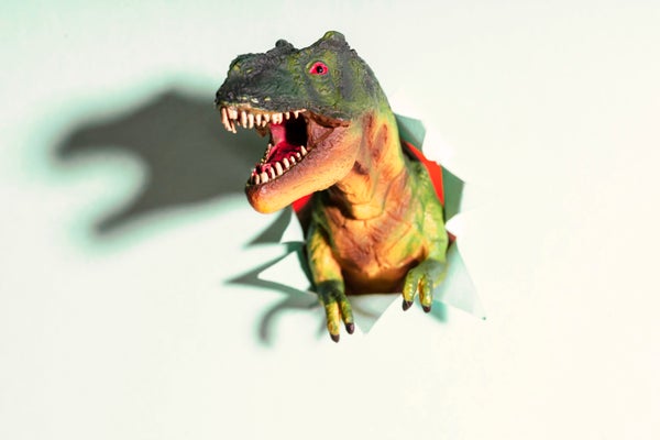 T-Rex toy bursting through paper, showing shadow.