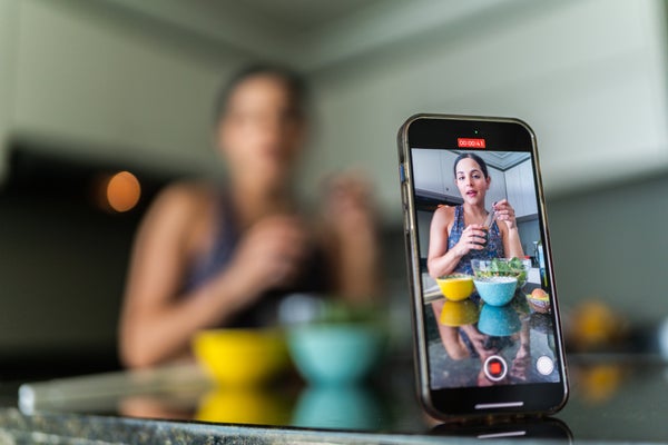 A woman in athleisure films herself making a salad.