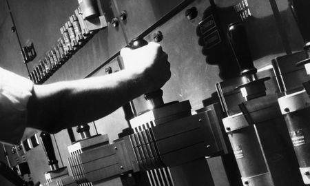 An arm grabs the lever of a large power switch, seemingly ready to pull it.