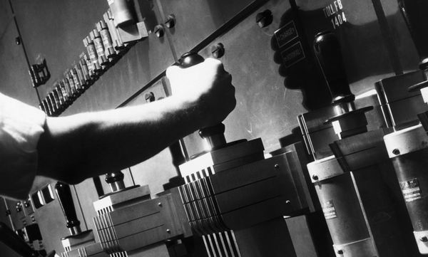 An arm grabs the lever of a large power switch, seemingly ready to pull it.