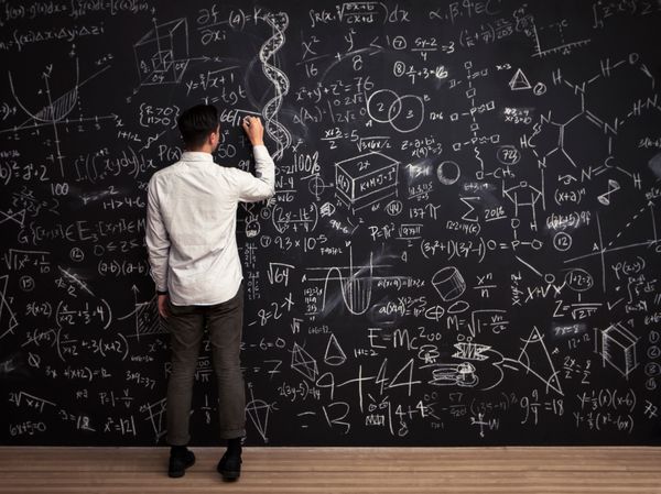Man writes mathematical equations on chalkboard.