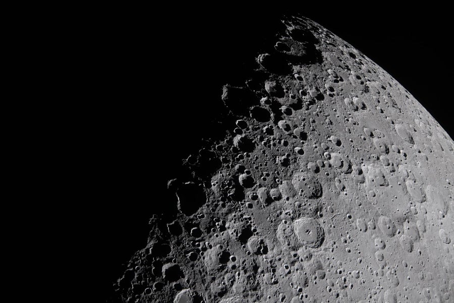 Close-up of a crater-covered moon with half obscured by darkness, the border crossing from bottom left to top right.