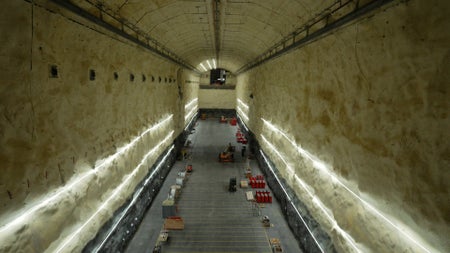 A long, high view of an enormous, empty cavern with some distant construction equipment in view.