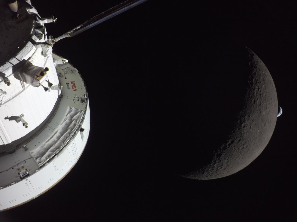 A la izquierda, parte de una nave espacial. A la derecha, una vista ampliada de la luna creciente, con una pequeña Tierra creciente justo a su derecha.