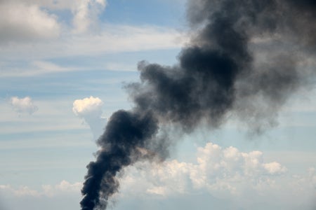 Blue sky with a trail of black smoke rising up