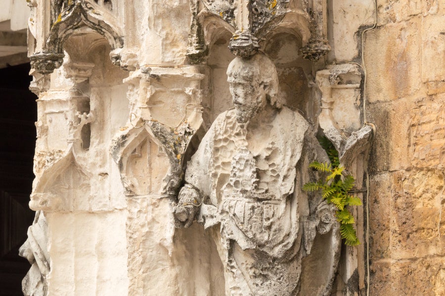 Ornate white stonework with a statue showing a person with visible pockmarks