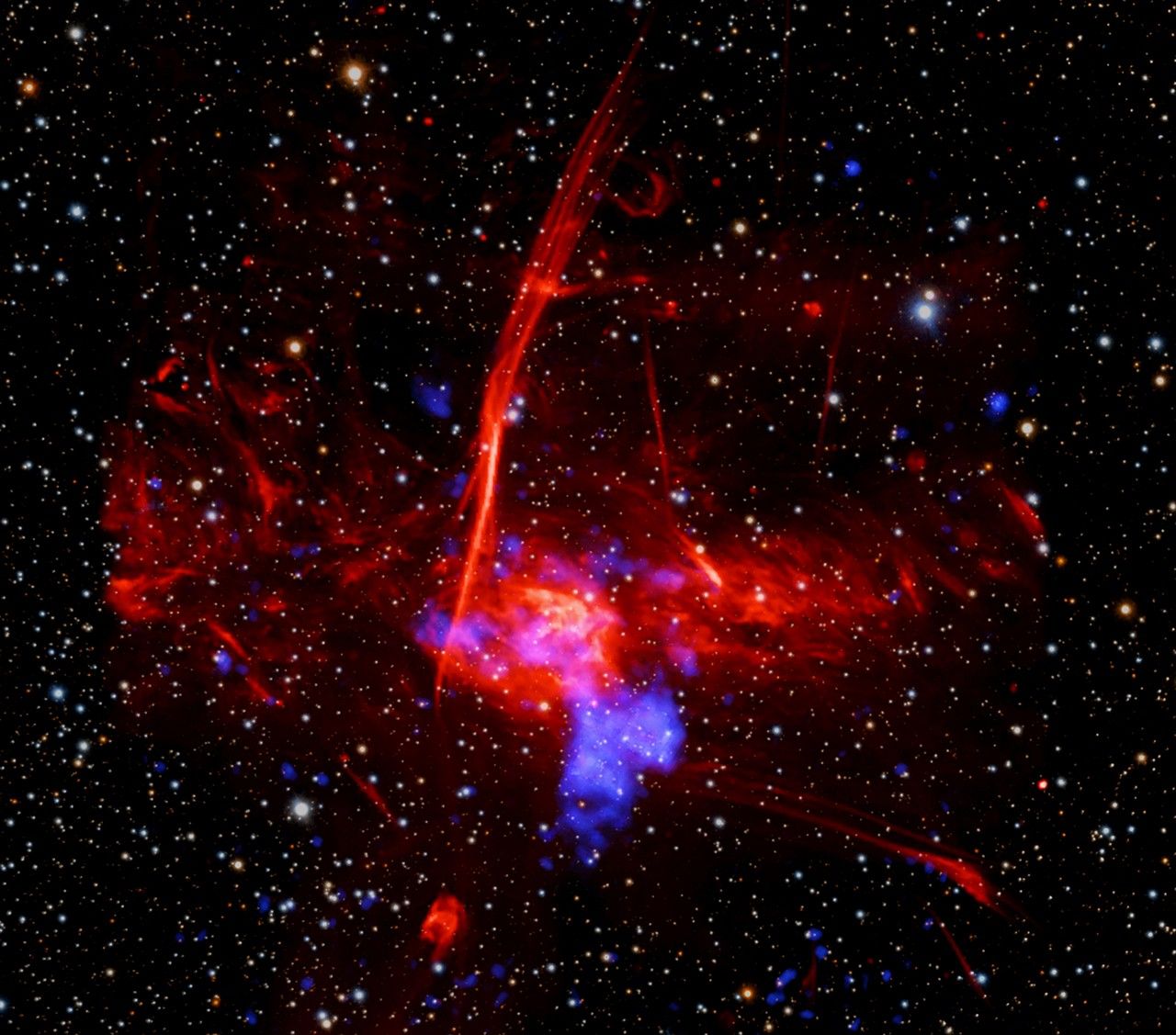 a composite image of colorful, overlapping clouds, which suggests to astronomers that a supernova remnant may be buried in gas near the center of our Milky Way galaxy
