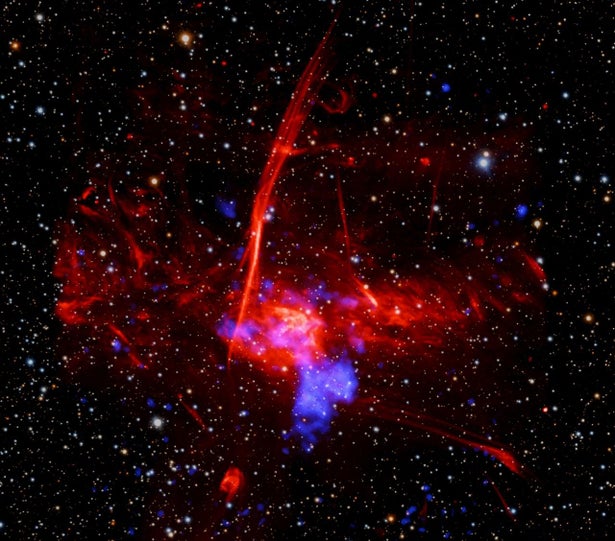 a composite image of colorful, overlapping clouds, which suggests to astronomers that a supernova remnant may be buried in gas near the center of our Milky Way galaxy