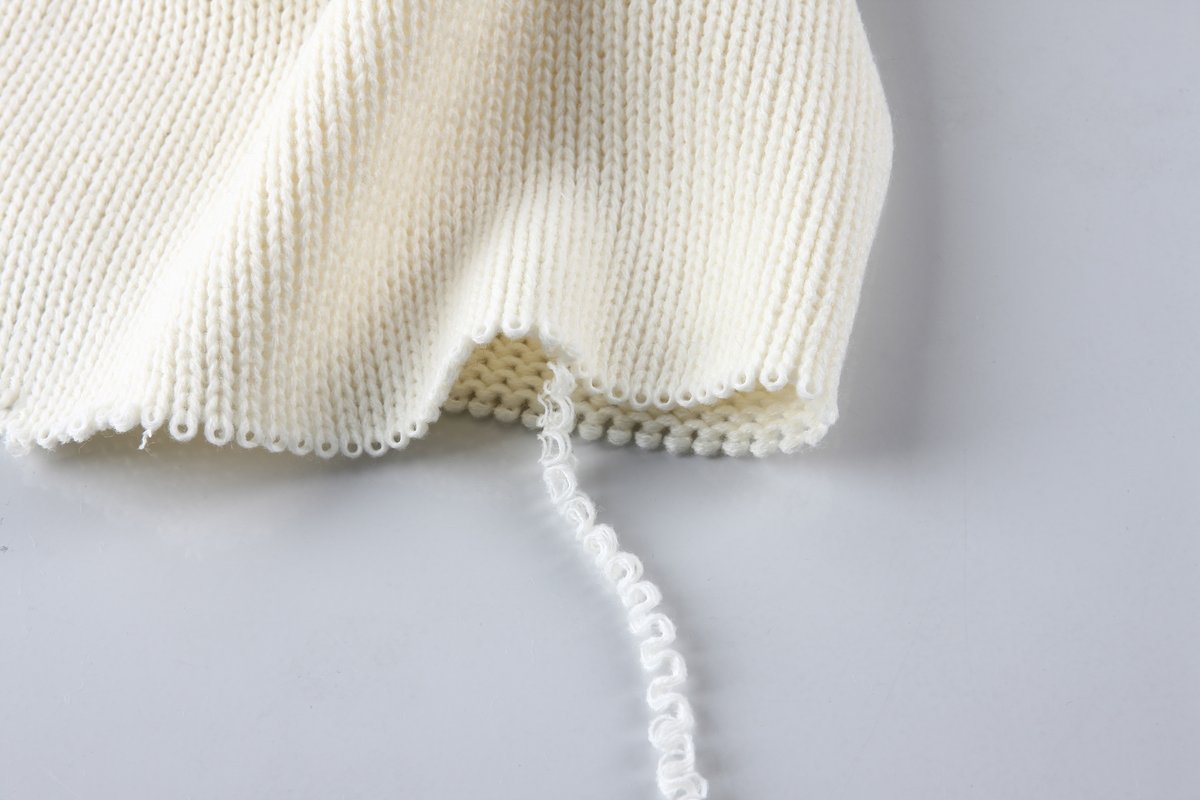 White knit yarn being pulled.