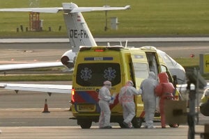 A person in a hazmat suit is escorted to a ambulance from a medical aircraft allegedly carrying some of the passengers from the cruise ship MV Hondius believed to be infected with hantavirus, at Schiphol airport near Amsterdam on May 6, 2026.