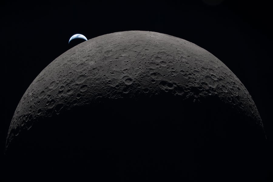 A view of half the moon’s disk, topped by a tiny crescent Earth.