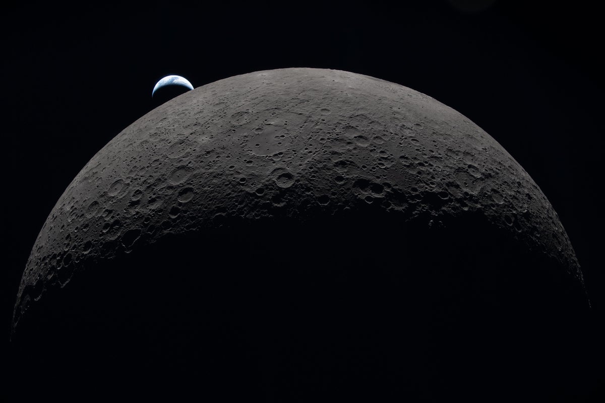 A view of half the moon's disk, topped by a tiny crescent Earth.