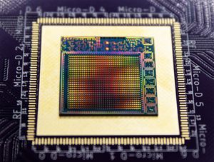 A chip with a rainbow reflection sits on a processor board.