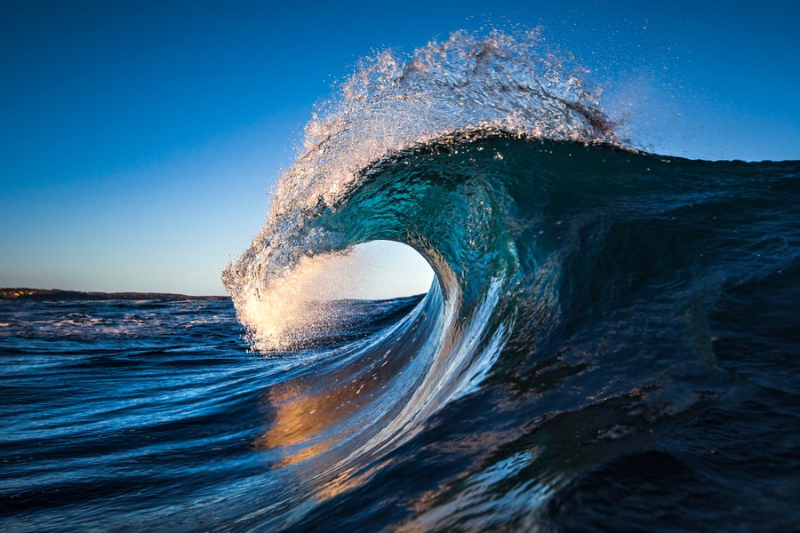 A sunlit, cresting ocean wave.