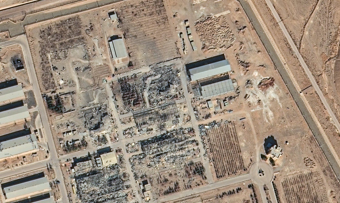 A satellite image looking directly down at an industrial complex in flat, brown landscape with visible damage to several buildings