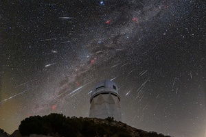 A telescope on a hilltop against a starlit night sky with meteors ablaze