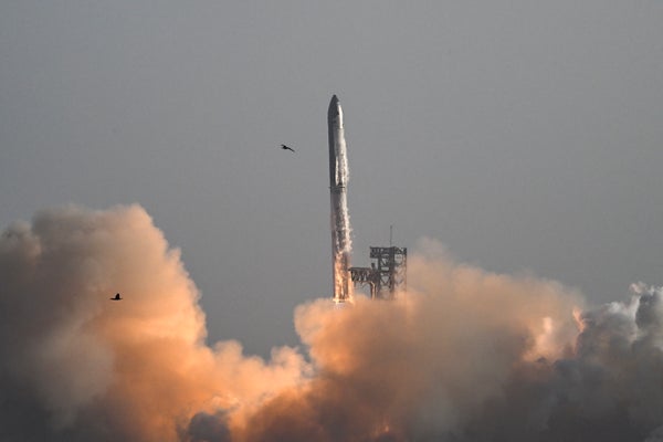 A rocket blasting off against a gray sky with a cloud of exhaust below it
