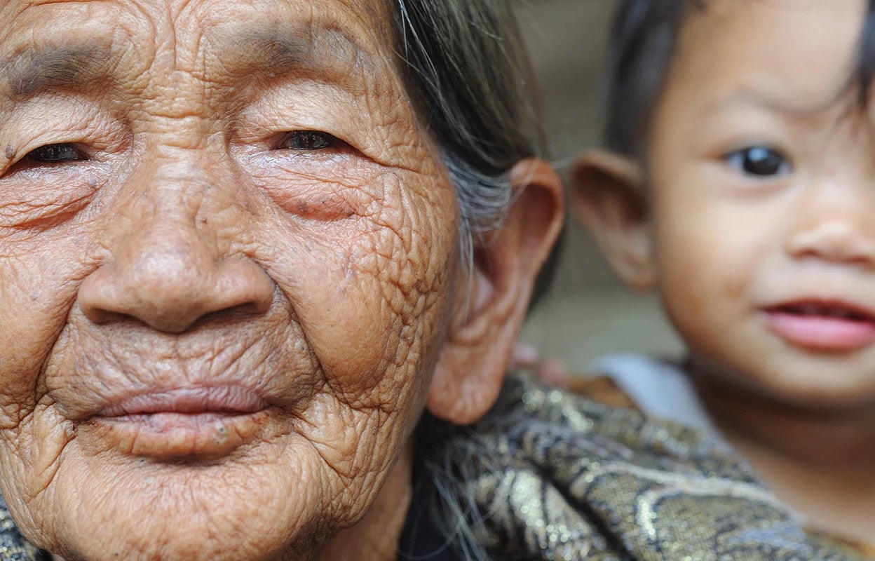 Close-up portrait of an elderly woman, with young child's face in the background.