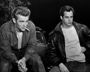 Actor James Dean smokes a cigarette beside another actor in a scene from Rebel without a Cause.