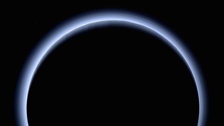 Pluto appears as a blue-silhouetted dark orb in this picture from NASA's New Horizons probe.