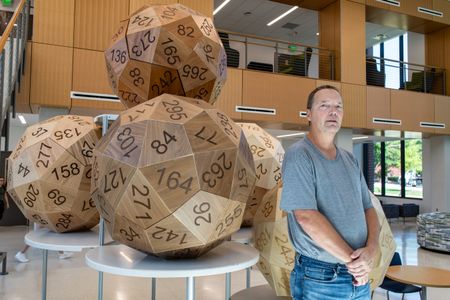 Eric Harshbarger stands in front of five large dice, each with a different number on each face.