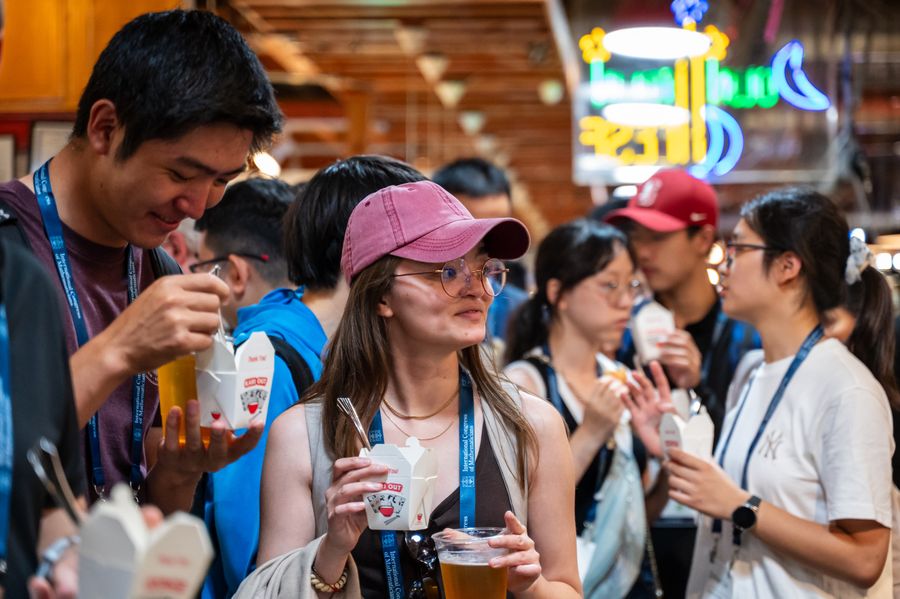 Young mathematicians holding beers and takeout containers, smiling and standing in circles